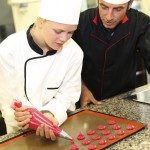 Student in pastry making cookies with help of teacher