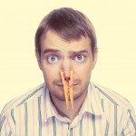 Portrait of caucasian man with orange clothespin on his nose - bad smell concept photography. Color toned image.