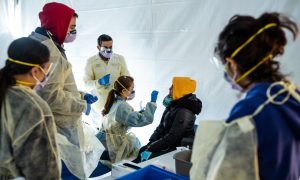 photo or medical staff checking employees for symptoms to show how to cope with COVID at work this winter