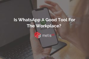 Metis HR blog title graphic. Photo of WhatsApp app on a mobile phone, being held in front of a laptop. Text reads 'Is WhatsApp A Good Tool For The Workplace?'.