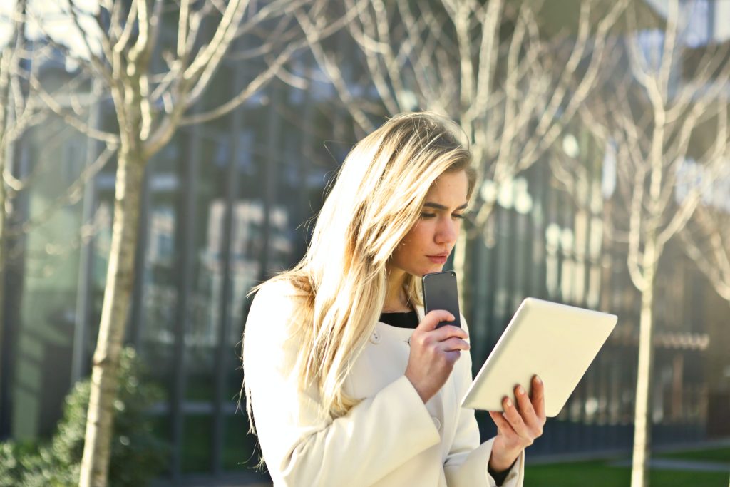 image shows a woman in a white jumper reading from a tablet