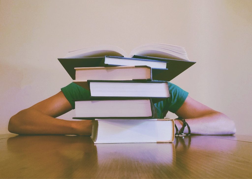 image shows a pile of book that represent Literacy Barriers In The Workplace