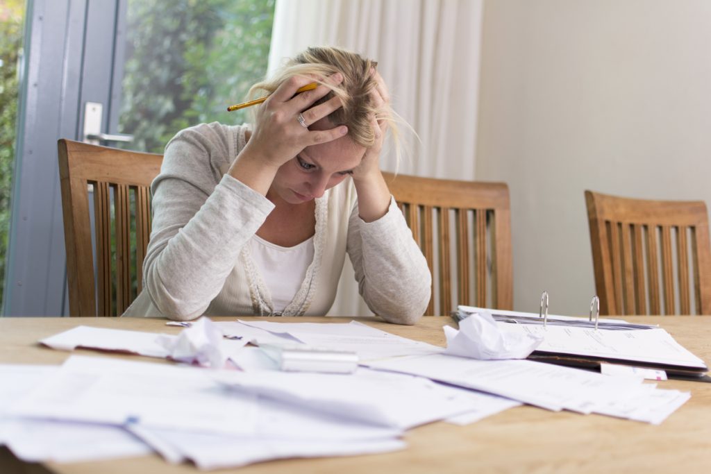 image of woman with head in hands looking at paperwork to depict pitfalls of writing your own contracts