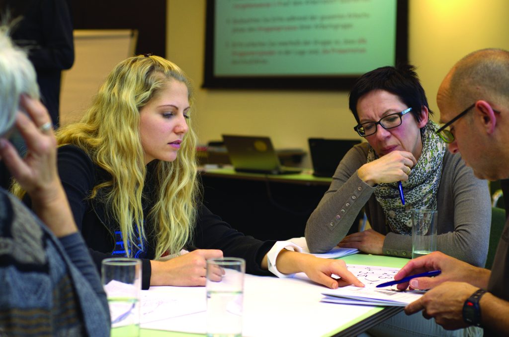 an image of older people and younger people workign together in the workplace